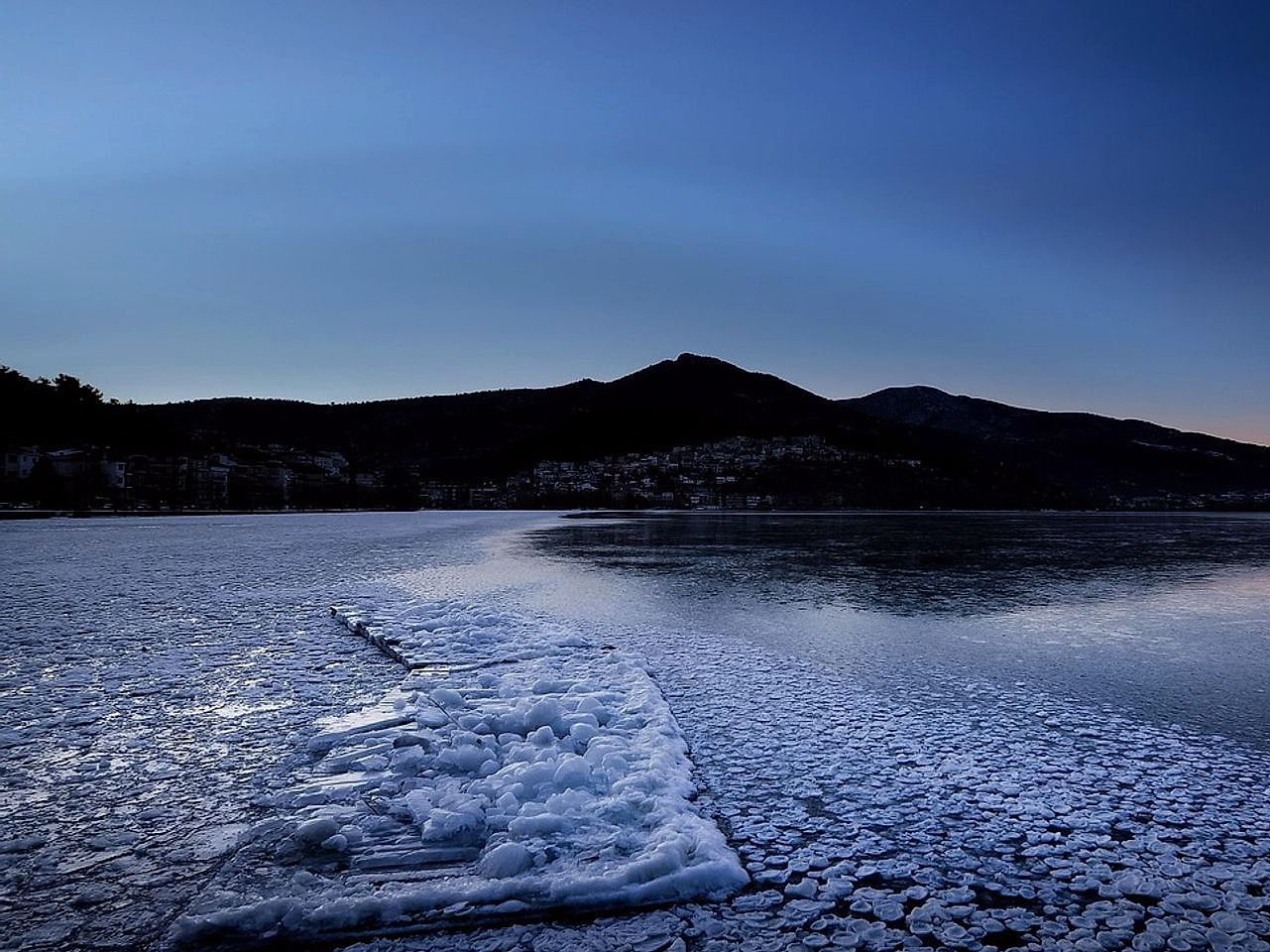 Uma linha de costa vista ao primeiro amanhecer sobre o lago sob o gelo